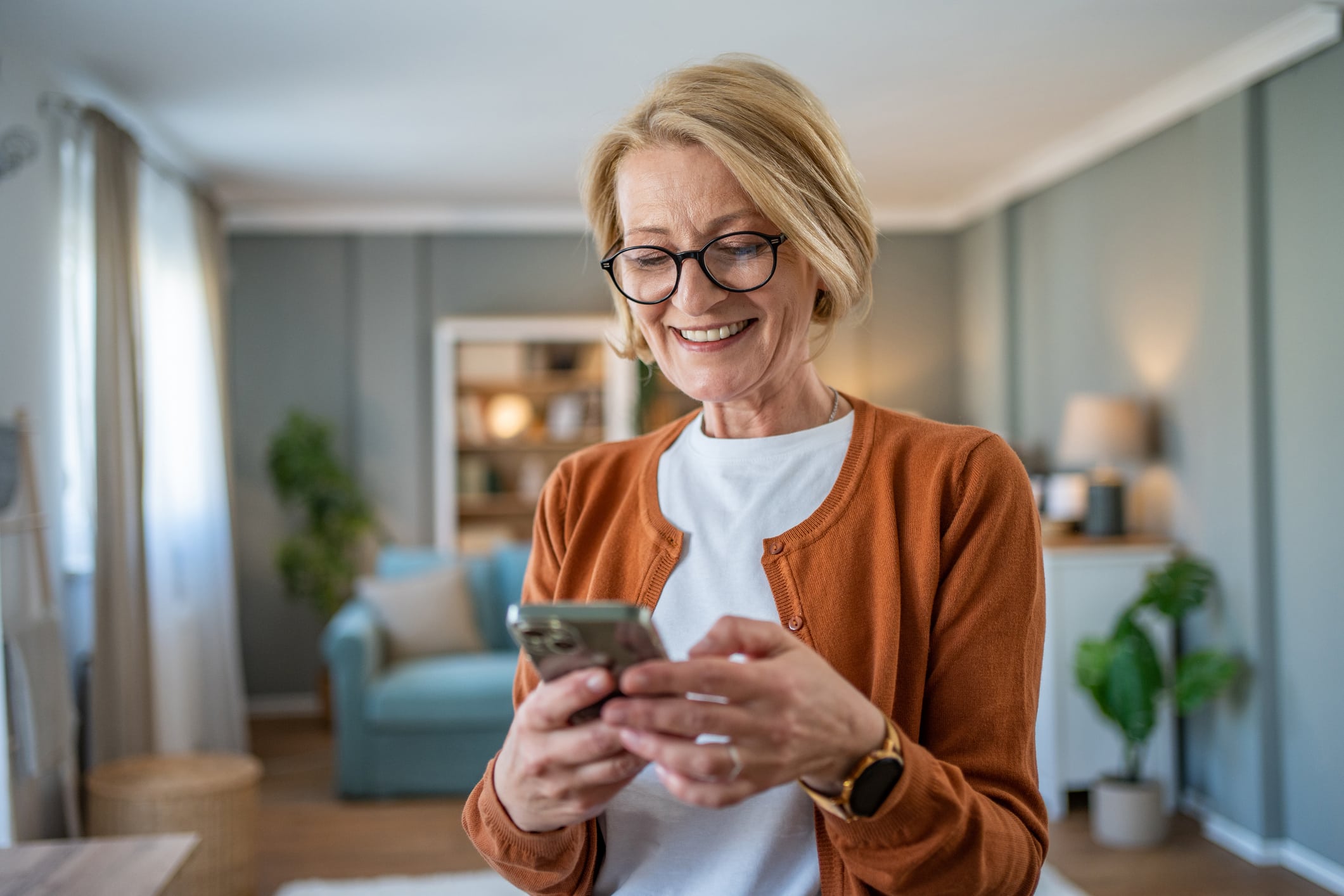 Mature woman using smartphone at home to surf the internet